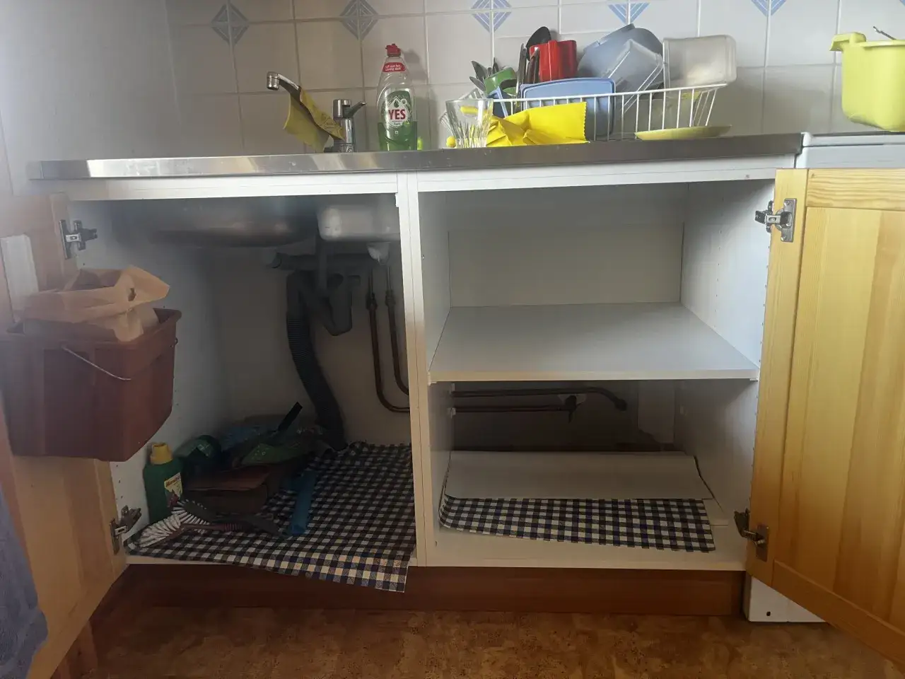 Under diskbänken förbereds plats för att installera diskmaskin. Rör och städmaterial syns.