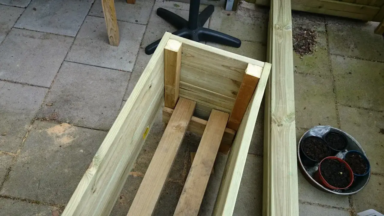 Påbörjat projekt att bygga blomlåda av tryckimpregnerat virke. Några krukor med jord står redo.