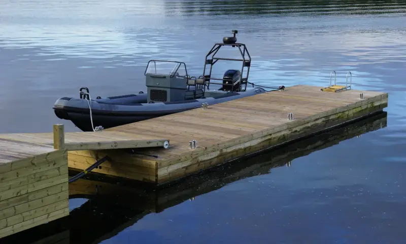 En grå RIB-båt ligger förtöjd vid en nybyggd flytbrygga. Perfekt för att bygga flytbrygga och njuta av vattnet.